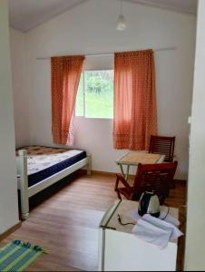 a small room with a bed and a table and a table sidx sidx at Sitio JP in Pindamonhangaba