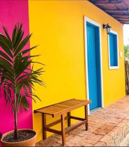 een houten bankje voor een kleurrijk huis bij Vila Borogodó BG in Barra Grande