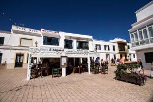 a group of people sitting at tables outside a building at Hostal S'Algaret in Fornells