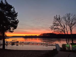 ein Sonnenuntergang über einem Gewässer mit einem Dock in der Unterkunft Domek 2 Wdechy in Wdzydze Kiszewskie