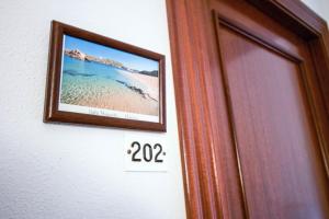 a picture of a beach on a wall next to a door at Hostal S'Algaret in Fornells