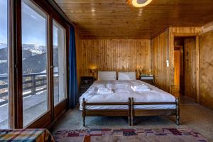 a bedroom with a bed and a large window at Chalet Fauvette in La Tzoumaz