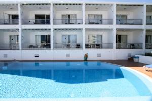 a large swimming pool in front of a building at Hostal S'Algaret in Fornells