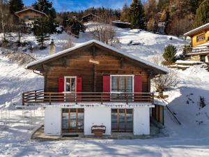 a wooden house with red doors in the snow at Chalet Fauvette in La Tzoumaz