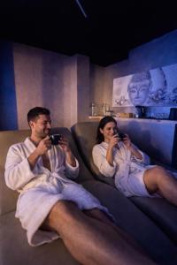 een man en een vrouw zitten op een bank en maken foto's bij ES Apartments in Nago-Torbole