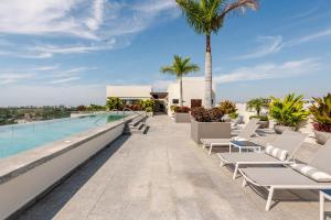 a resort infinity pool with lounge chairs and a palm tree at Luxury Condo en Nuevo Vallarta Alberca Tipo Resort in Nuevo Vallarta