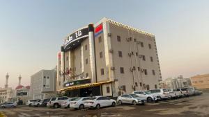 a large building with cars parked in a parking lot at تاج الملكه للشقق المخدومة in Ḑirs
