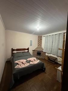 een slaapkamer met een bed in een kamer met een open haard bij Pousada Taquaral in Bocaina de Minas