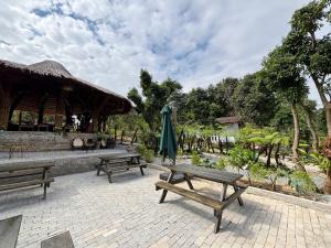 a group of picnic tables and an umbrella at Chậm Viên Le Jardin in Thanh Lâm
