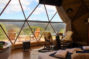a bedroom with a large window with a table and chairs at Le Refuge Urubici in Urubici