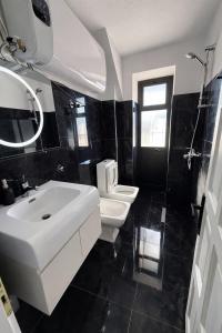 een zwart-witte badkamer met een wastafel en een toilet bij Shkodra Apartment AR in Shkodër