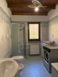 a bathroom with a shower toilet and a washing machine at Al Cacciatore in Gallio