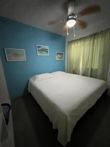 ein Schlafzimmer mit einem weißen Bett mit einer blauen Wand in der Unterkunft Raya apartment in Ixtapa + 25 Fotos