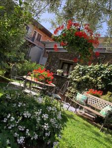 un giardino con panchine e fiori di fronte a un edificio di La Casetta dei Fiori sull Etna a Ragalna