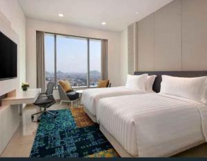 een slaapkamer met 2 bedden, een bureau en een televisie bij Denox house in Tanjungkarang