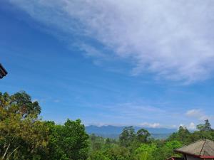 a blue sky with trees and mountains in the background at Mountain View in Bandarawela