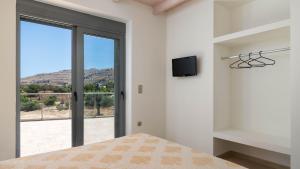 una camera da letto con un letto e una TV a parete di Lindos Summer Memories Villas a Líndos
