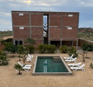 een bakstenen gebouw met een zwembad en ligstoelen bij Baja69 lodge in El Pescadero