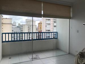 Cette chambre dispose d'un balcon offrant une vue sur la ville. dans l'établissement Pitangueiras Apartment, great location, oceanfront, à Guarujá