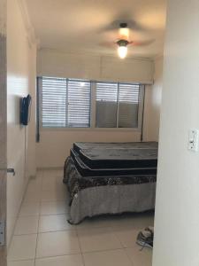 une chambre avec un lit et un ventilateur de plafond dans l'établissement Pitangueiras Apartment, great location, oceanfront, à Guarujá