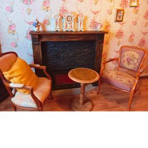 een woonkamer met een open haard met 2 stoelen en een tafel bij Emporium in Lobbes