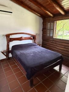 a bed sitting in a room with a window at Cabañas La Cautiva in Tanti