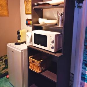 un micro-ondes posé sur une étagère à côté d'un réfrigérateur dans l'établissement Emporium, à Lobbes