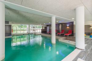 een zwembad met rode stoelen in een gebouw bij Résidence Pierre & Vacances La Petite Venise in Colmar