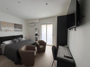 a bedroom with a bed and a chair and a television at Umberto Home 303 in Catania