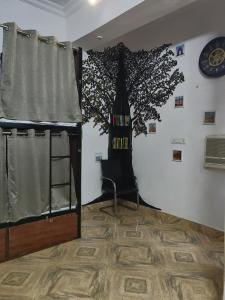 een kamer met een muurschildering van een boom en een stoel bij Green Olive in Lucknow +9 foto's