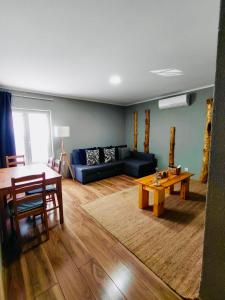 een woonkamer met een blauwe bank en een tafel bij Tree House II in Setúbal
