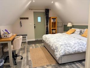 a bedroom with a bed and a desk and a table and chair at The Honeysuckle Coop in Grantham