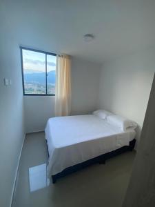 a white bedroom with a bed and a window at Apartamento confortable, excelente ubicacion in Ibagué