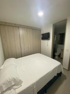 a large white bed in a room with a toilet at Apartamento confortable, excelente ubicacion in Ibagué