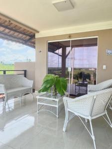 a patio with white chairs and a table with a plant at Casa Campos do Mar in Conde