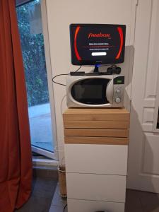 een magnetron bovenop een dressoir met een tv bij Studio avec jacuzzi in Saint-Fons