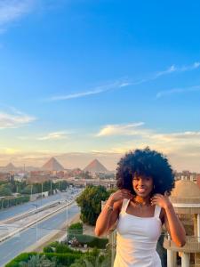 een vrouw met krullend haar die bovenop een gebouw staat bij Pyramids sunrise inn in Caïro
