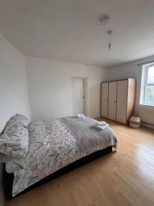 a white bedroom with a bed and a wooden floor at NextDoor Morden in Merton