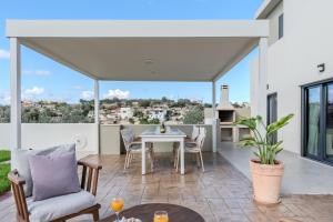 een woonkamer met een tafel en stoelen op een patio bij Dina Villa in Roumelí
