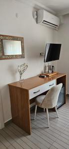 a desk with a television and a chair in a room at OTELIA PANSIYON in Ayvalık