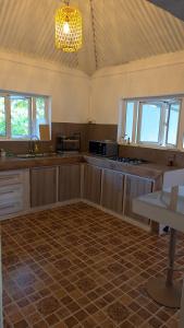 a large kitchen with wooden cabinets and a chandelier at Kaz Kreol in Trou d'Eau Douce +2 photos