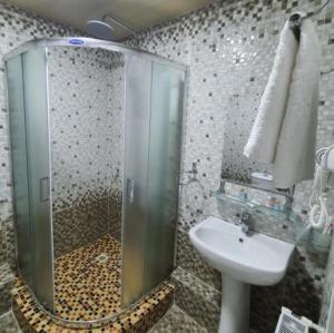 un bagno con doccia in vetro e lavandino di Reikartz Namangan a Namangan Altre 25 foto