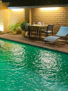 een tafel en stoelen naast een zwembad bij HÔTEL Assinie LODGE in Assinie