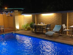 een zwembad 's nachts met een tafel en stoelen bij HÔTEL Assinie LODGE in Assinie