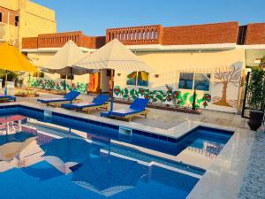 a swimming pool with chairs and umbrellas next to a building at Horus Golden Luxor in Luxor