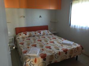 a bed in a room with a bedspread with books on it at Camping Village Stella Mare in Lacona +179 photos