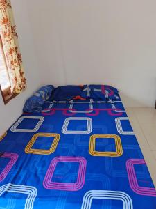 a bed with a blue comforter and pillows on it at Alkache in Wonosari