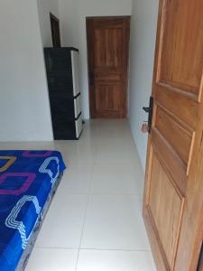 a room with a door and a bed and a refrigerator at Alkache in Wonosari