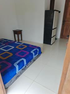a bedroom with a blue bed and a refrigerator at Alkache in Wonosari