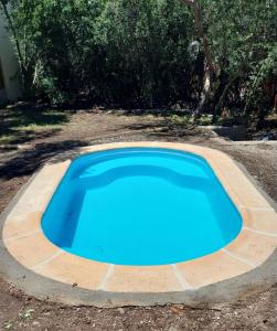 une grande piscine bleue dans une cour dans l'établissement Cabaña Wairaluna, à Capilla del Monte